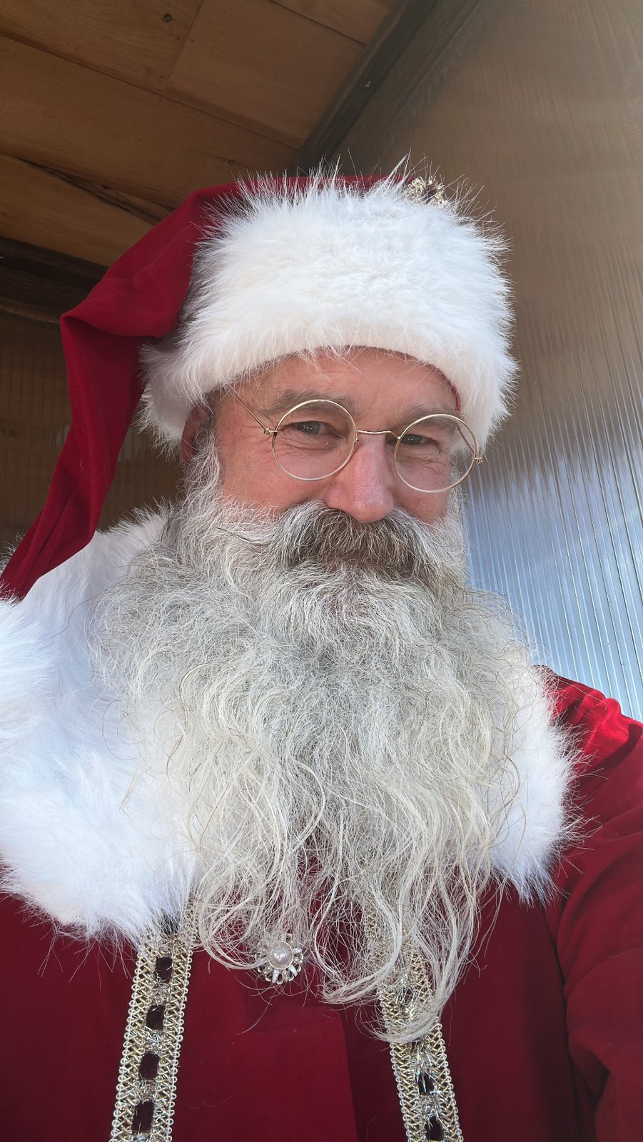 Close-up portrait of Santa in a red velvet hat and wire-rim glasses with a full white beard