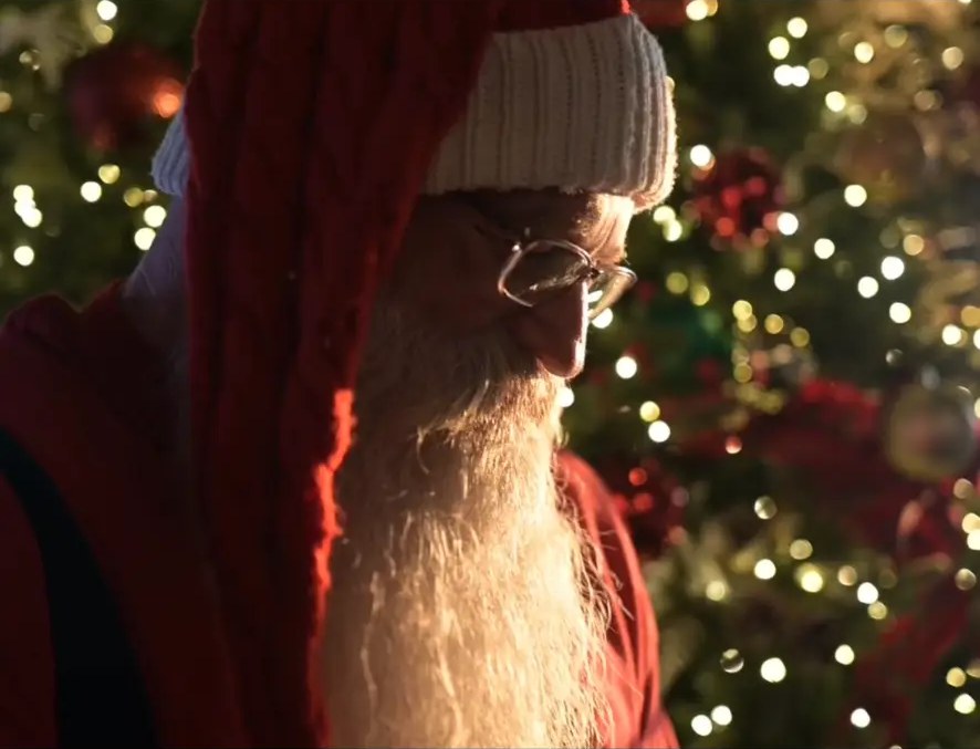 Cinematic profile of Santa lit by the glow of a Christmas tree